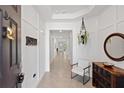 Inviting entryway featuring a coat rack, mirror, table and chair and views into the open concept floor plan at 17108 Harvest Moon Way, Bradenton, FL 34211