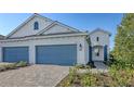 The white exterior of this two-story home is complemented by its well-maintained lawn and blue garage doors at 2309 Blue Mahoe Ln, Sarasota, FL 34240