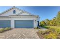 Two-story home exterior featuring a two car garage, brick driveway and manicured landscaping at 2309 Blue Mahoe Ln, Sarasota, FL 34240