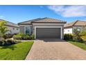 Beautiful home showcasing an attached two-car garage, gray paint, tile roof, paver driveway, and well manicured lawn at 3110 Tolmino Ct, Bradenton, FL 34211