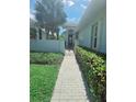 Charming home entrance featuring a brick walkway, manicured hedges, and tropical palm trees at 321 Reclinata Cir, Venice, FL 34292