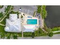 Aerial view of a community pool with lounge chairs, palm trees, and well-maintained landscaping next to a parking area at 7730 34Th W Ave # 103, Bradenton, FL 34209
