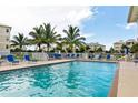 Outdoor pool surrounded by comfortable lounge chairs and palm trees with multiple condo buildings visible in the background at 7730 34Th W Ave # 103, Bradenton, FL 34209