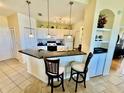 Bright kitchen with white cabinetry, black granite countertops, tile flooring, and barstool seating at 8351 38Th Street E Cir # 302, Sarasota, FL 34243