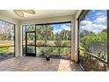 Screened-in patio with brick flooring, offering views of the lush greenery and blue sky, creating a relaxing outdoor space at 17440 Hampton Falls Ter, Bradenton, FL 34202