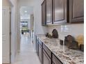 Gourmet butler's pantry with extended granite counters, white subway tile backsplash, and dark wood cabinetry at 18320 Thistleberry Pl, Lakewood Ranch, FL 34211