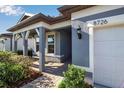 Charming home exterior featuring a covered porch, manicured landscaping, and a two-car garage at 8726 Backshore Ln, Parrish, FL 34219