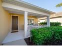 Inviting front porch with white pillars, a ceiling fan, a welcome mat, and lush landscaping at 12140 Whisper Lake Dr, Bradenton, FL 34211