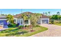 Beautiful single-story home showcasing a two-car garage, lush landscaping, and a brick driveway at 18115 Littleton Pl, Bradenton, FL 34202