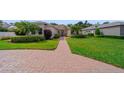 Charming single-story home with a brick driveway, green lawn, and manicured shrubs at 2114 147Th E Ct, Bradenton, FL 34212
