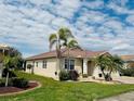 Beautiful home with a well-manicured lawn, mature trees, and classic clay tile roofing at 2160 Chenille Ct, Venice, FL 34292