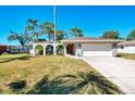 Attractive single-story home showcasing a well-manicured lawn, mature trees, and an arched portico at the entrance at 2221 Pine View Cir, Sarasota, FL 34231