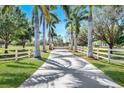 Long driveway lined with palm trees and white fencing creates an appealing entrance to the property at 3551 Ridgeland Ct, Punta Gorda, FL 33982