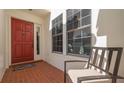 Inviting front entrance with a bright red door, red tile flooring, and a comfortable seating area at 4404 Calle Serena, Sarasota, FL 34238