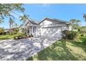 Charming single-story home with a well-manicured lawn, blue front door, and a brick driveway leading to an attached garage at 4933 Rutland Gate, Sarasota, FL 34235