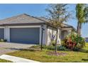 Charming home featuring a gray garage door, gray tile roof, and lush landscaping at 5311 White Sand Cv, Bradenton, FL 34211