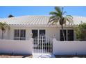 View of the property's entrance gate with manicured landscaping and white tiled roof at 618 Gladstone Ln, Holmes Beach, FL 34217