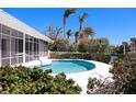 A blue in-ground pool surrounded by lush landscaping in a screened-in enclosure at 618 Gladstone Ln, Holmes Beach, FL 34217