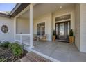 Covered front porch with rocking chairs and a stylish entrance, welcoming visitors at 6540 The Masters Ave, Lakewood Ranch, FL 34202