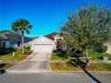 Inviting single-story home with a well-manicured lawn, mature tree, and a two-car garage at 718 Tanana Fall Dr, Ruskin, FL 33570