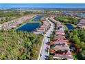 Aerial view of a neighborhood featuring homes with tile roofs, a nearby lake, and lush landscaping at 9902 Craftsman Park Way, Palmetto, FL 34221