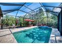 Beautiful screened-in pool with patio furniture, an umbrella, and lush landscaping, perfect for outdoor relaxation at 9902 Craftsman Park Way, Palmetto, FL 34221