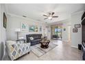 Bright living room with neutral walls, tile flooring, modern ceiling fan, and sliding doors to the outside at 10008 Carnoustie Pl, Bradenton, FL 34211
