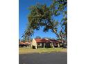 Serene view of a home with a red tile roof, complemented by mature trees and a well-manicured lawn at 1216 58Th W St, Bradenton, FL 34209