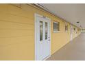 Exterior hallway featuring unit entrance with white door, painted yellow walls, and overhead lighting at 2155 Wood St # A20, Sarasota, FL 34237