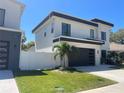 Contemporary home showcasing modern design with a dark garage door, stone accents, and well-kept lawn at 3204 W Grace St, Tampa, FL 33607