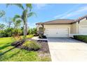 Home showcasing an attached two-car garage, well-maintained lawn, and a beautifully landscaped garden bed at 324 Casalino Dr, Nokomis, FL 34275