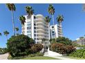 Exterior view of the condo building showing lush greenery, palm trees, and rounded balconies at 455 Longboat Club Rd # 407, Longboat Key, FL 34228