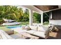 An open concept outdoor living area with a pool, summer kitchen, patio seating, and lush tropical views at 4644 Higel Ave, Sarasota, FL 34242