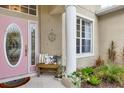 Inviting front porch features a decorative pink door, a cozy bench with pillows, and lush greenery at 5806 43Rd E Ct, Bradenton, FL 34203