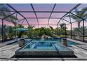 Screened-in pool with waterfall features, lush tropical landscaping, and a relaxing spa at 604 166Th E St, Bradenton, FL 34212