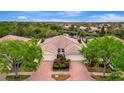 Aerial view of a well-maintained home featuring a brick driveway and beautiful landscaping at 7655 Pesaro Dr, Sarasota, FL 34238