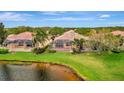 Backyard view featuring a screened lanai overlooking the lush green space and pond at 7655 Pesaro Dr, Sarasota, FL 34238