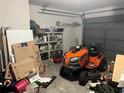 View of a cluttered garage with a lawn tractor and various storage items at 10443 Keystone St, Spring Hill, FL 34608
