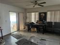 View of the living room with tile floors, ceiling fan, sliding glass door, vertical blinds, and clutter at 10443 Keystone St, Spring Hill, FL 34608