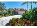 Beautiful single-story home featuring lush landscaping, mature palms, and a spacious driveway leading to an attached two-car garage at 107 Wayforest Dr, Venice, FL 34292