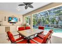 Covered patio with dining table, ceiling fan, tv, and built-in grill overlooks screened pool at 11835 Hollyhock Dr, Lakewood Ranch, FL 34202
