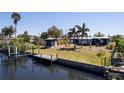 Aerial view of a waterfront property with a dock, a shed, a well-maintained lawn, and mature trees at 125 Palmetto Ne Cir, Port Charlotte, FL 33952