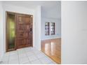 Bright foyer featuring tile flooring, a wooden front door with sidelight, and views into the living space at 314 Signorelli Dr, Nokomis, FL 34275