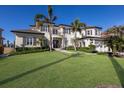 A luxurious two-story home featuring a well-manicured lawn, mature palms, and elegant architectural details at 348 W Royal Flamingo Dr, Sarasota, FL 34236