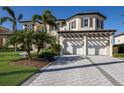 Spacious three-car garage with a stone paver driveway and mature landscaping at 348 W Royal Flamingo Dr, Sarasota, FL 34236