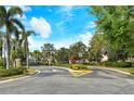 Community entrance featuring a paved road, manicured landscaping and a secure black iron gate at 5450 Soapstone Pl # 9-103, Sarasota, FL 34233
