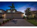 Charming two-story home featuring a paved driveway, two-car garage, and meticulously landscaped front yard at twilight at 6708 Grand Estuary Trl # 104, Bradenton, FL 34212