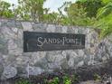 Stone entrance sign for Sands Point community surrounded by lush greenery and landscaping at 100 Sands Point Rd # 225, Longboat Key, FL 34228