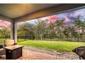 Covered patio overlooking a spacious, fenced backyard with lush green grass and mature trees at 14616 20Th E St, Parrish, FL 34219