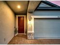 Close up of the main door and garage, showcasing the brick-paved entrance and warm exterior lighting at 14616 20Th E St, Parrish, FL 34219